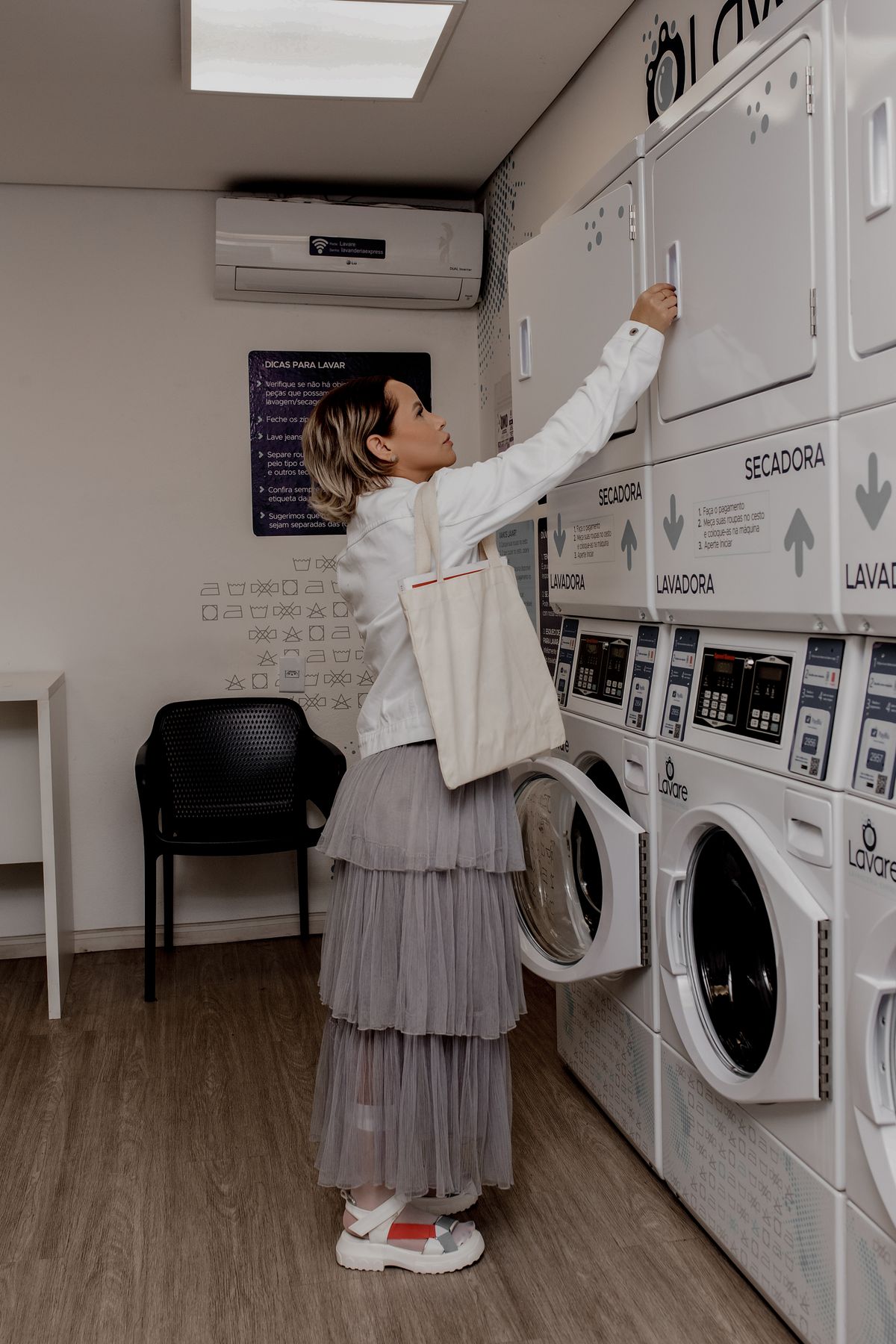 Customer loading a washing machine in a laundromat